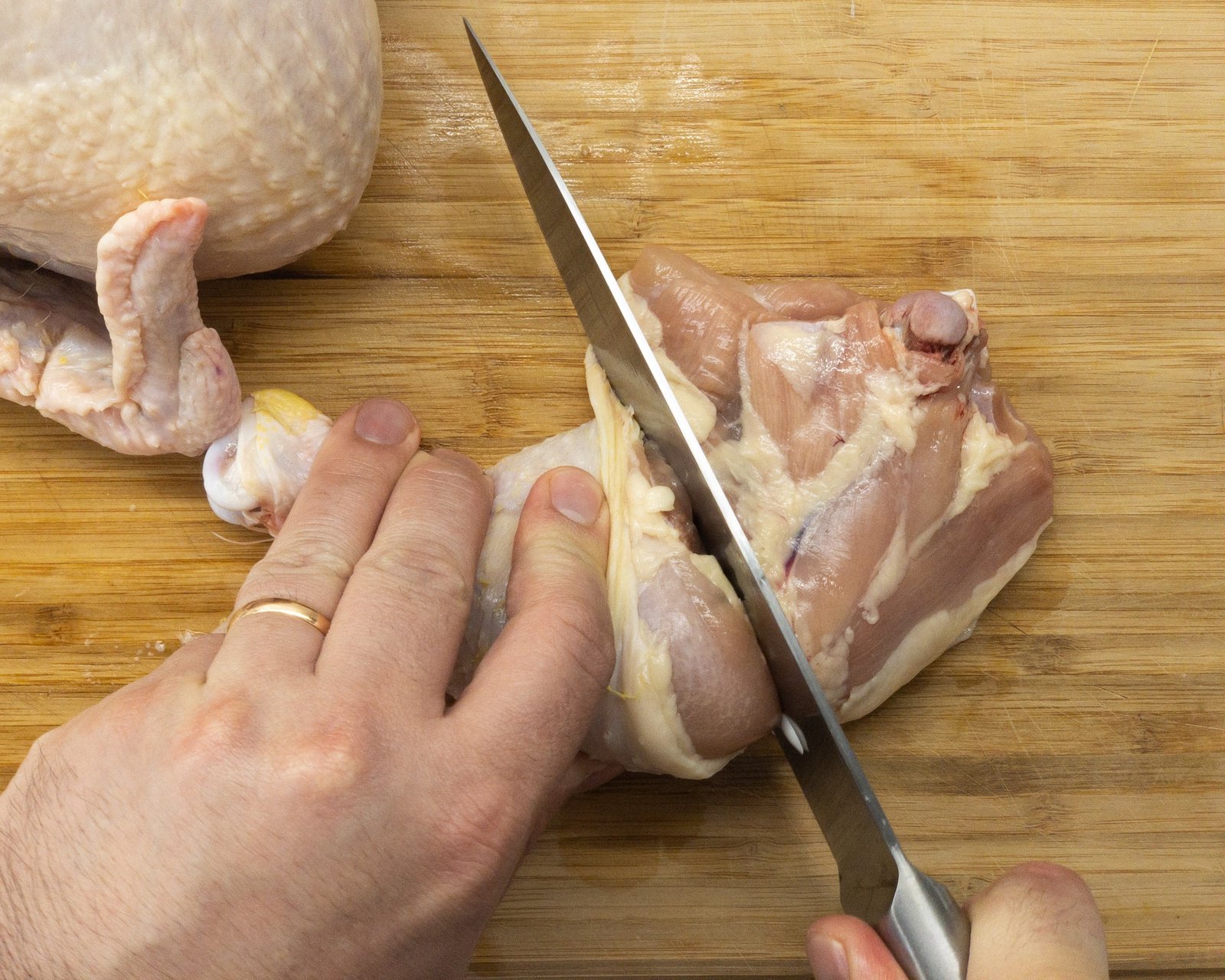 Separating the drum stick from the thigh of a chicken