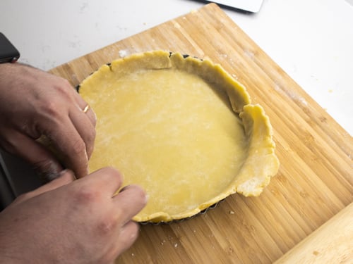 A tart tin being filled with pastry