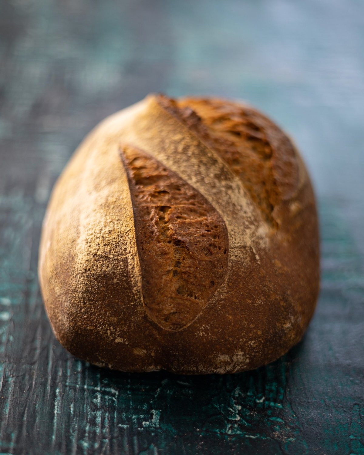Golden-brown sourdough batard loaf with scored crust and open crumb