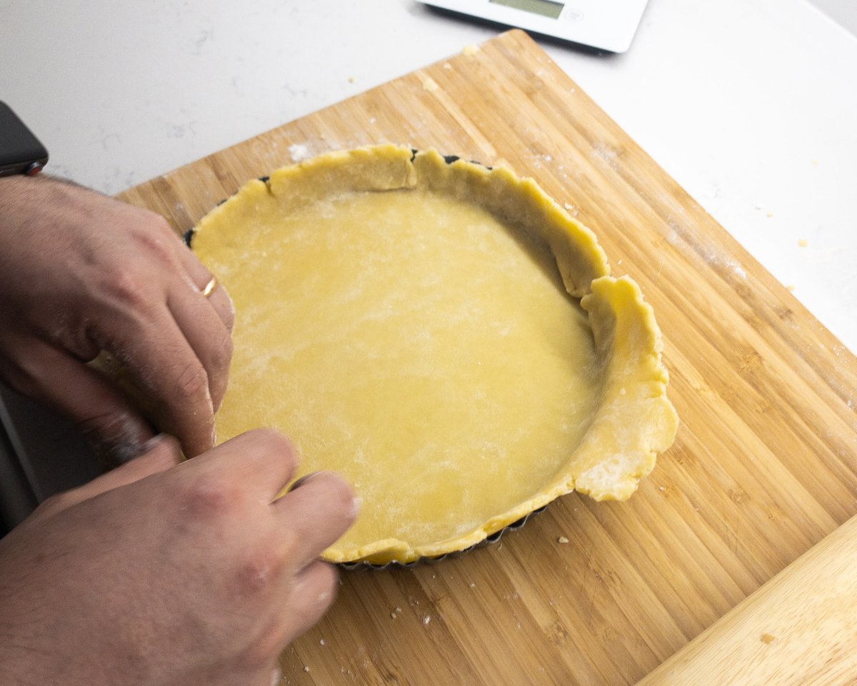 A tart tin being filled with pastry