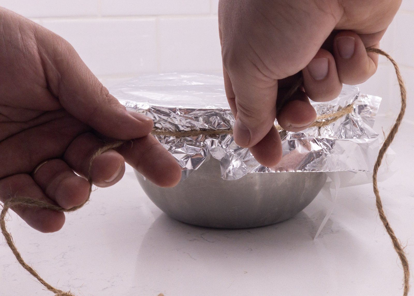 Bowl with foil on top being secured with string