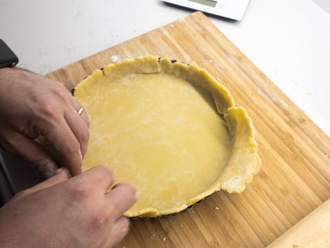 A tart tin being filled with pastry